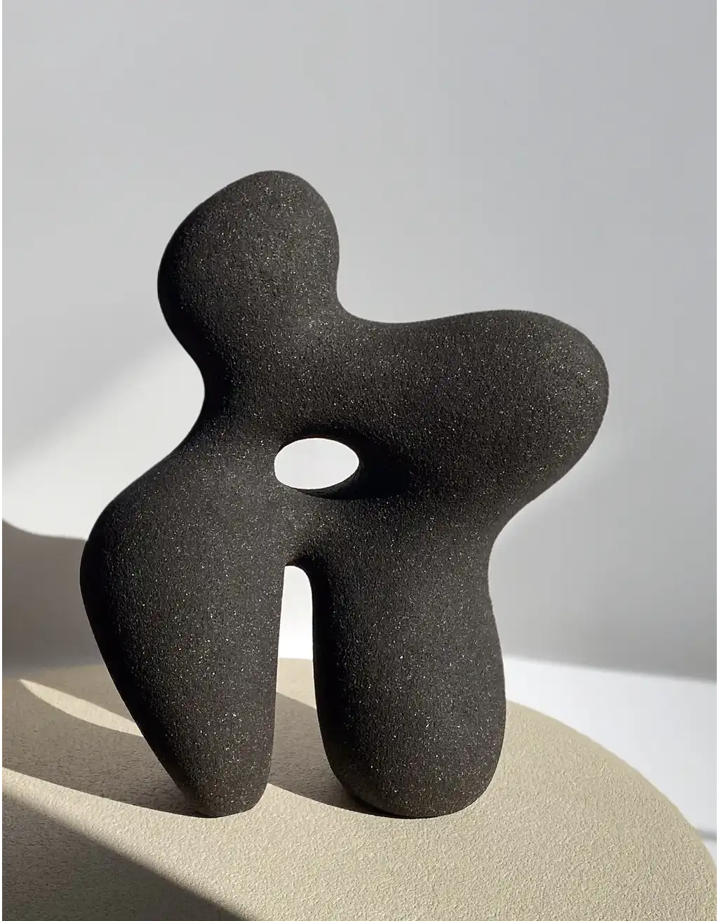 An abstract black sandstone sculpture made by Hermine Bourdin representing a woman's body with organic shapes.