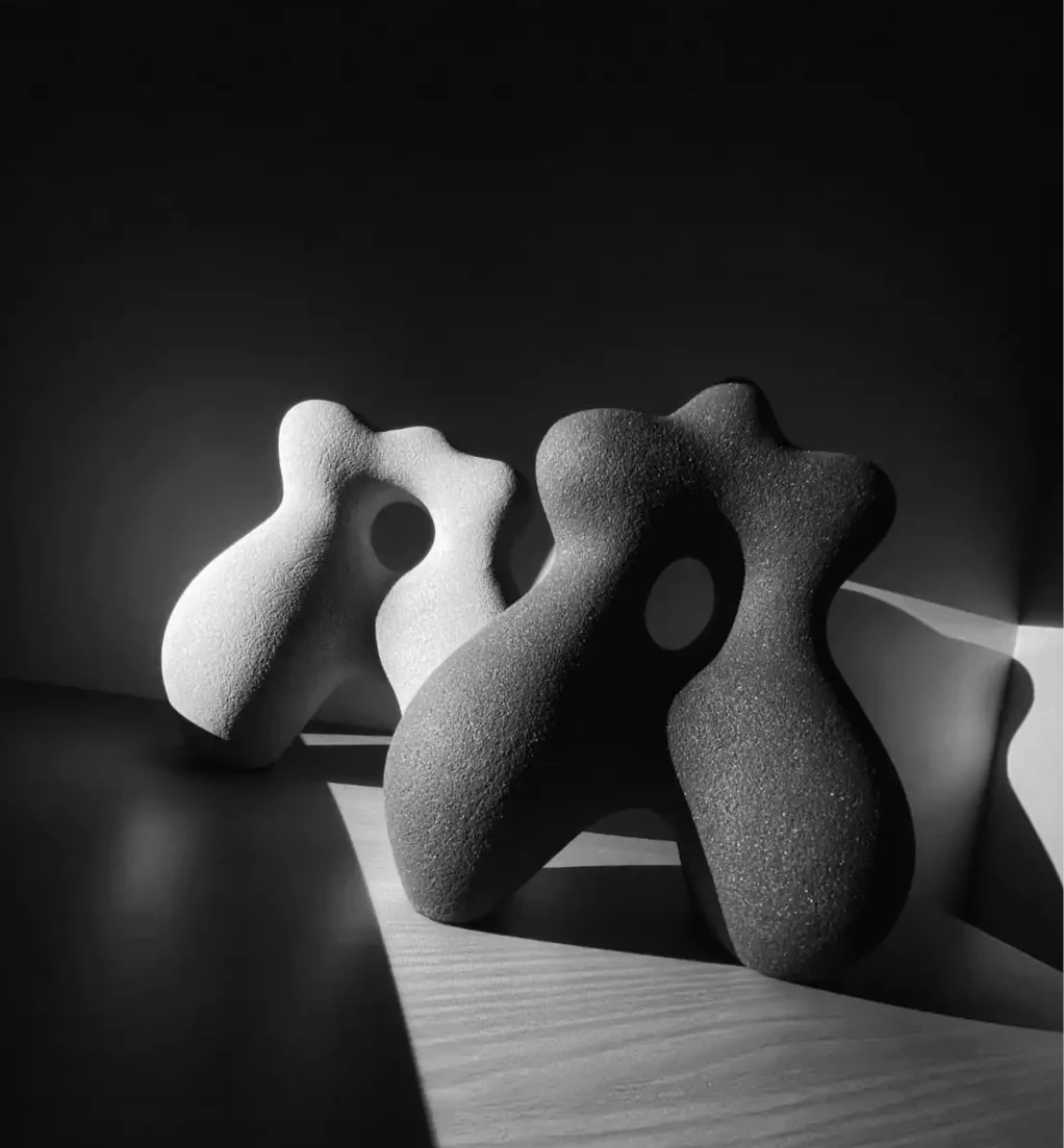 Two abstract sculptures by Hermine Bourdin, one white and one black, with organic rounded forms.